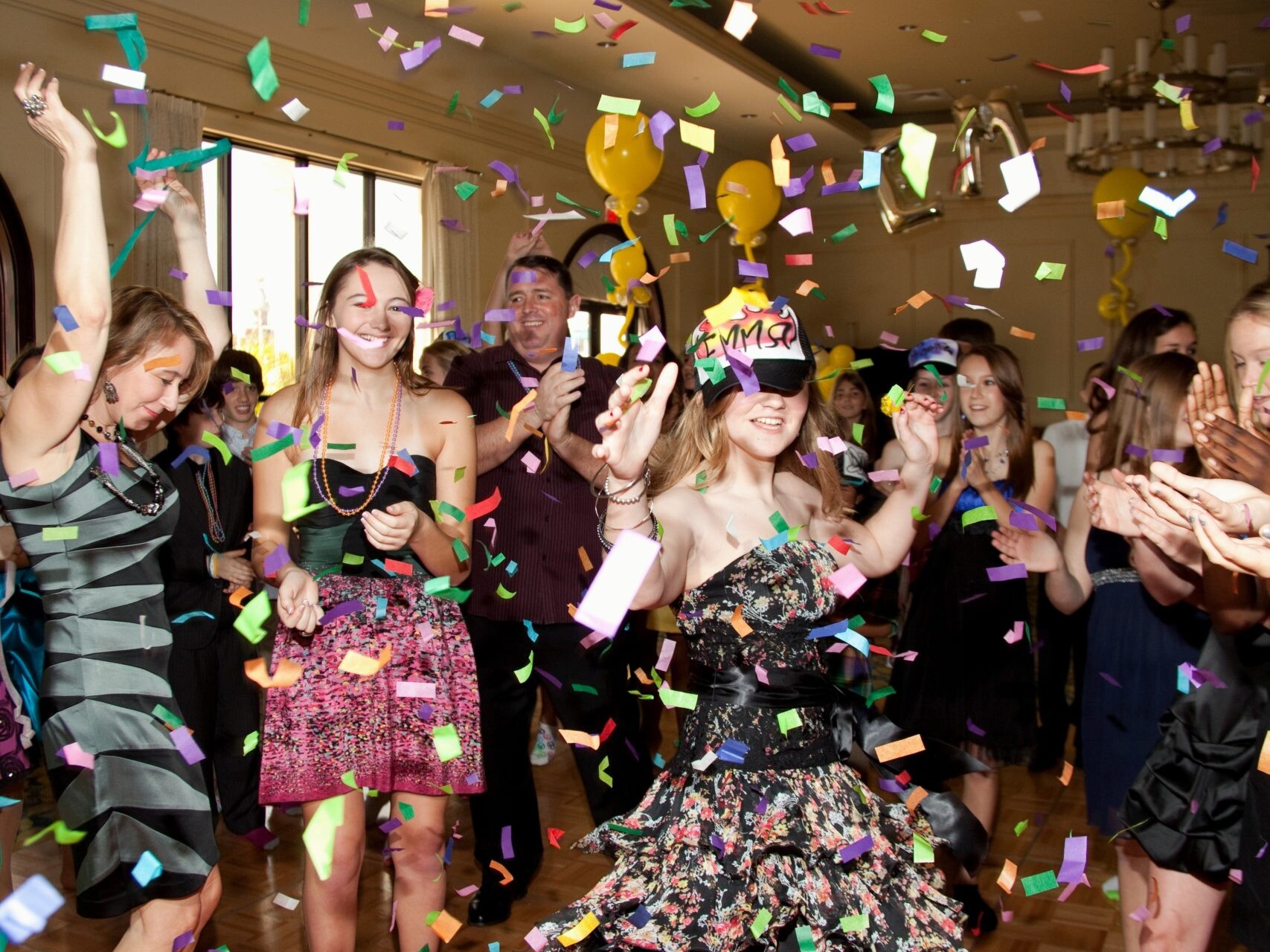 Girls smiling, clapping, dancing, and having fun at a party with confetti falling for a bar mitzvah event.