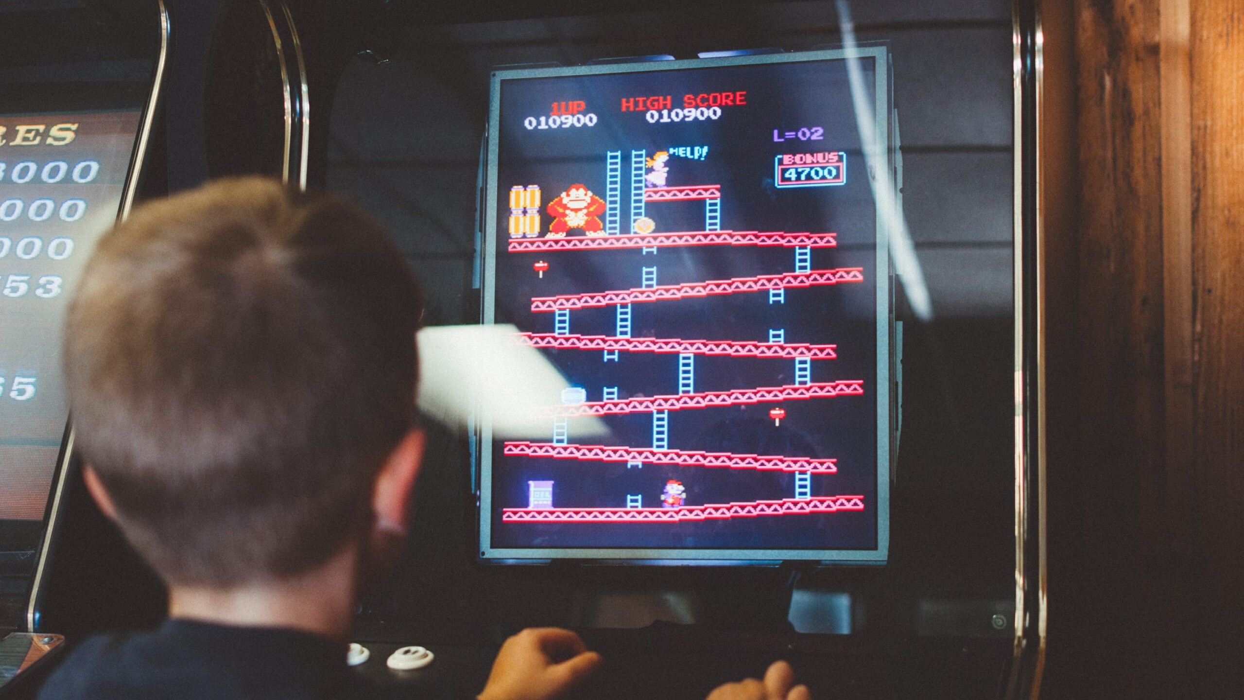 A kid playing a classic donkey Kong arcaded game.