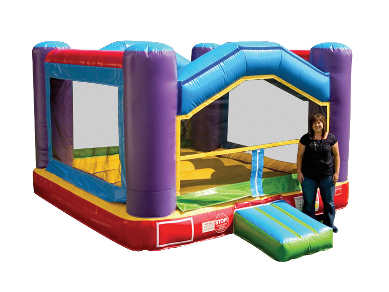 A woman standing and smiling next to a kids inflatable bouncy playground jump rental.