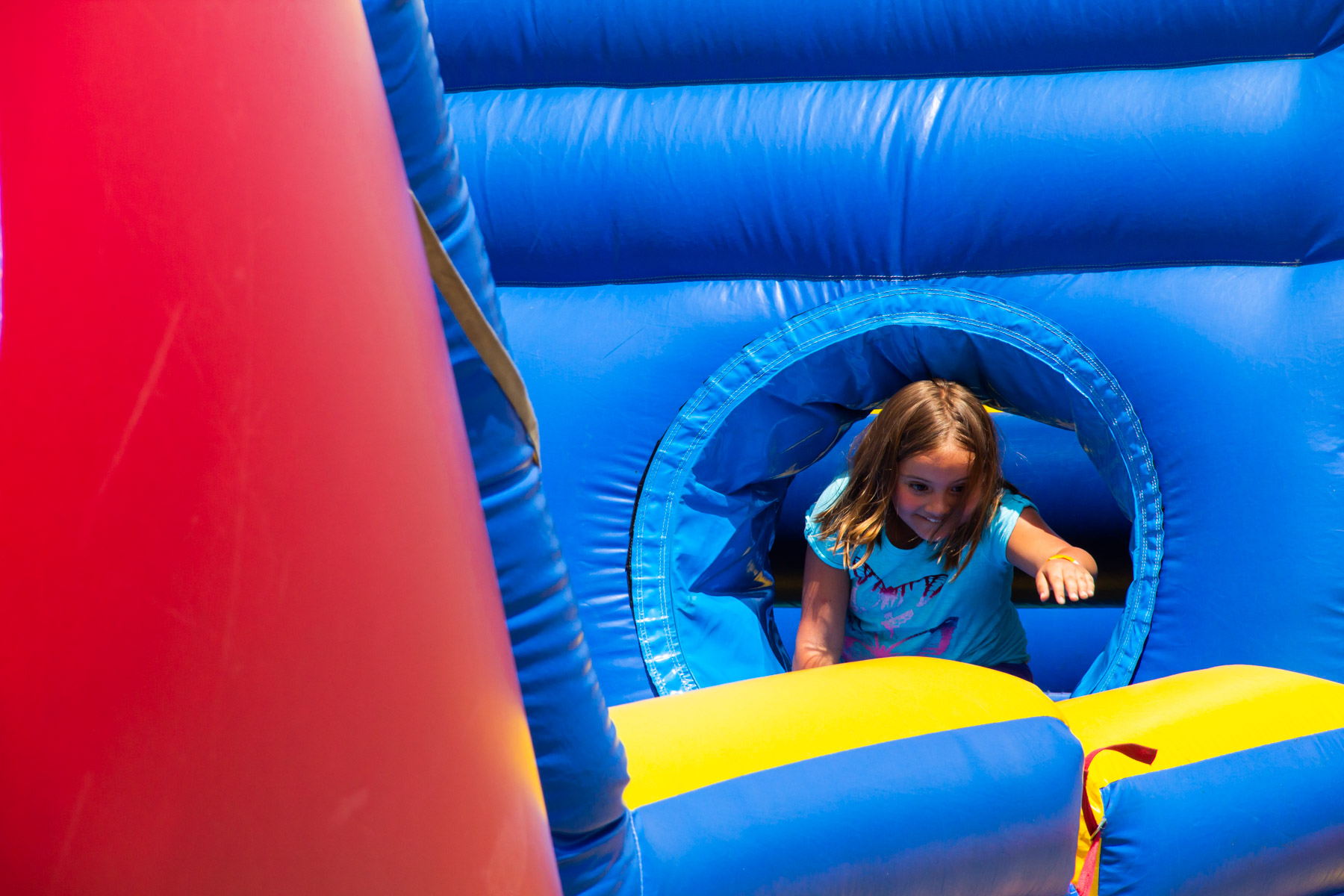 Girl climbing through inflatable obstacle course smiling and having fun.
