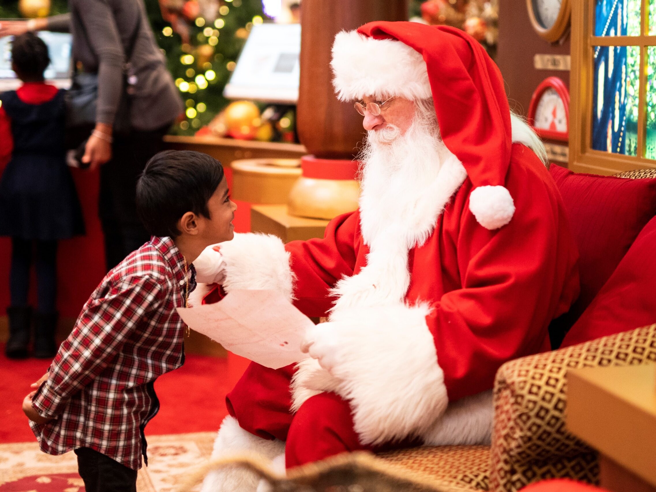 A small kid talking to Santa at a holiday event.