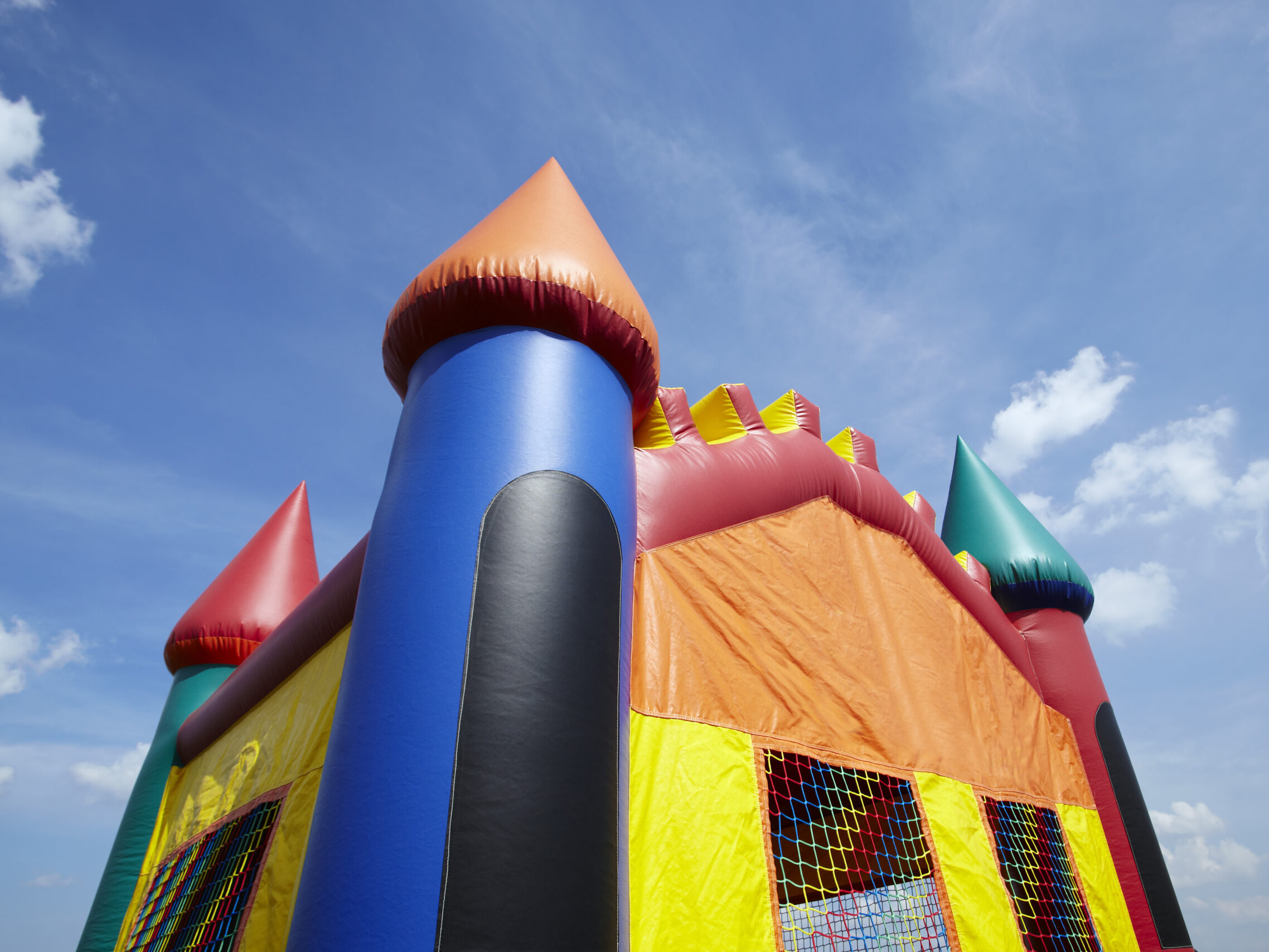 Children's inflatable bouncy castle with a blue sky and clouds.
