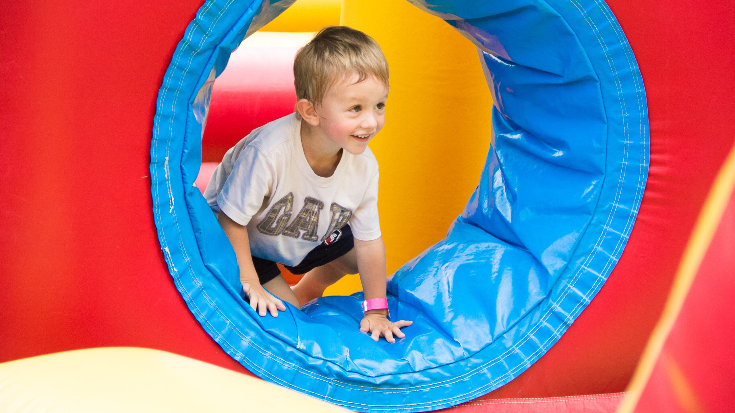 Boy climbing through inflatable obstacle course smiling and having fun.