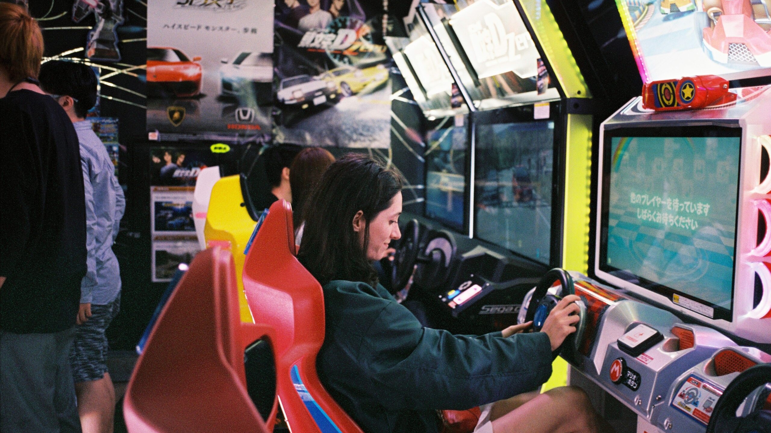 Girl smiling as she plays a Mario Cart arcade racing game at an event.