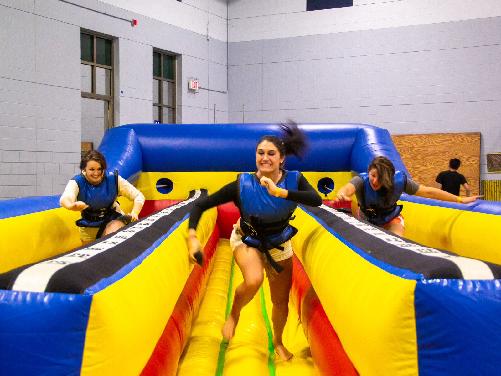 A group of friends smiling, running and having fun on an inflatable bungee run.