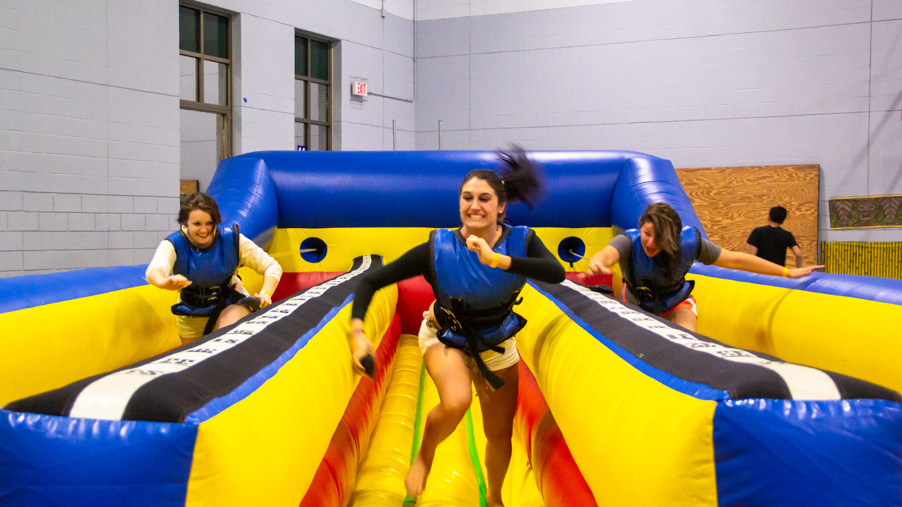 A group of friends smiling, running and having fun on an inflatable bungee run.