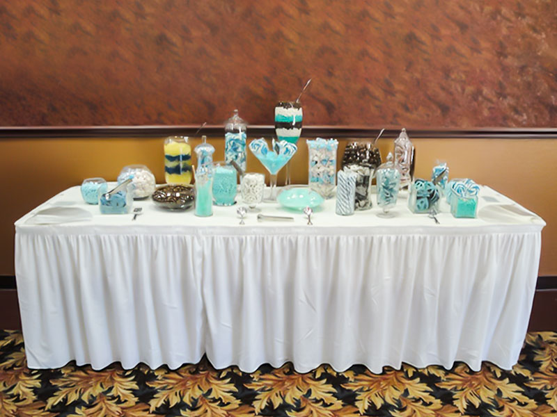 Table with sweets in glass containers on a table with a white skirt.