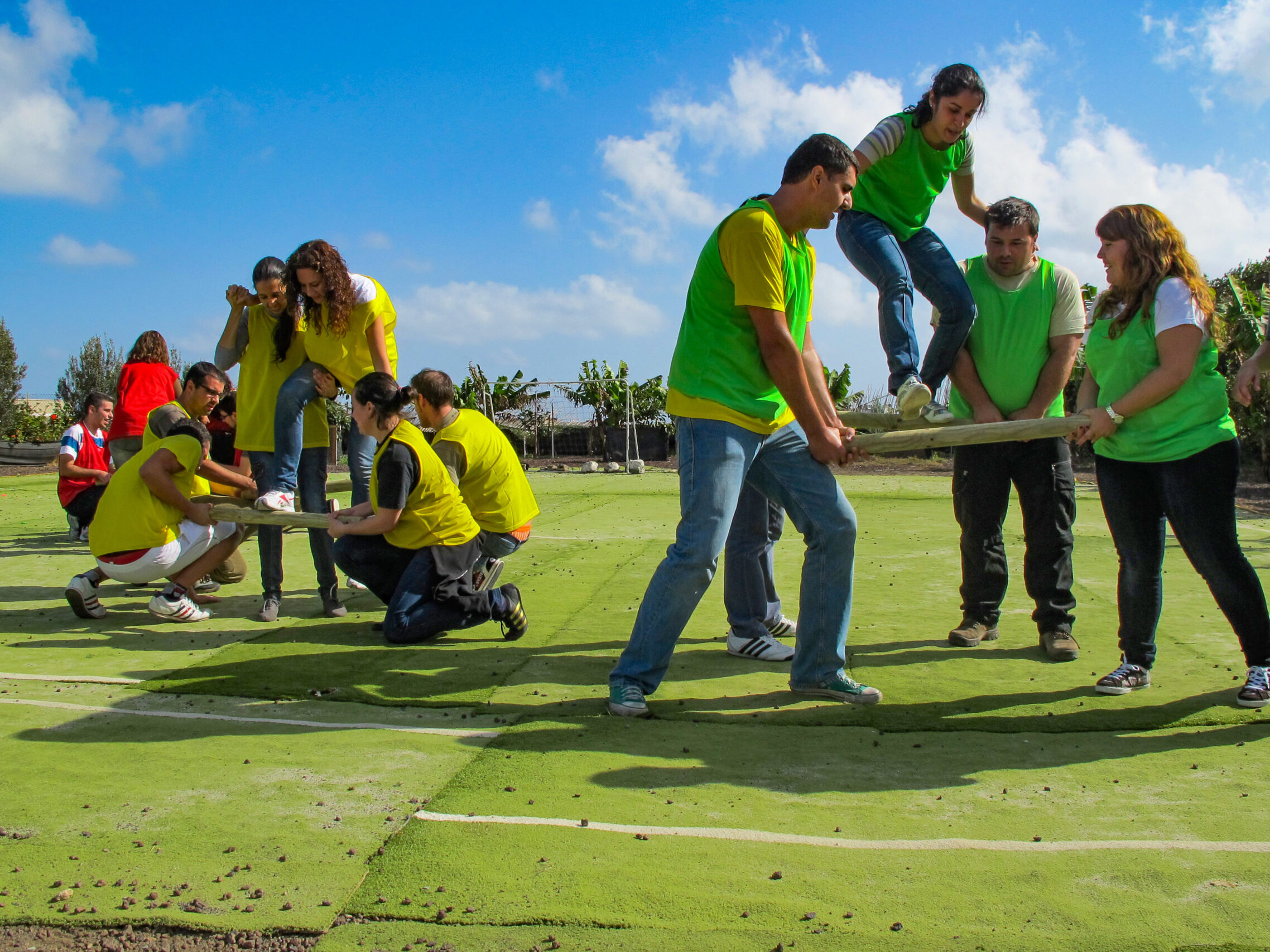 A group of people wearing green playing a team building game on a green field