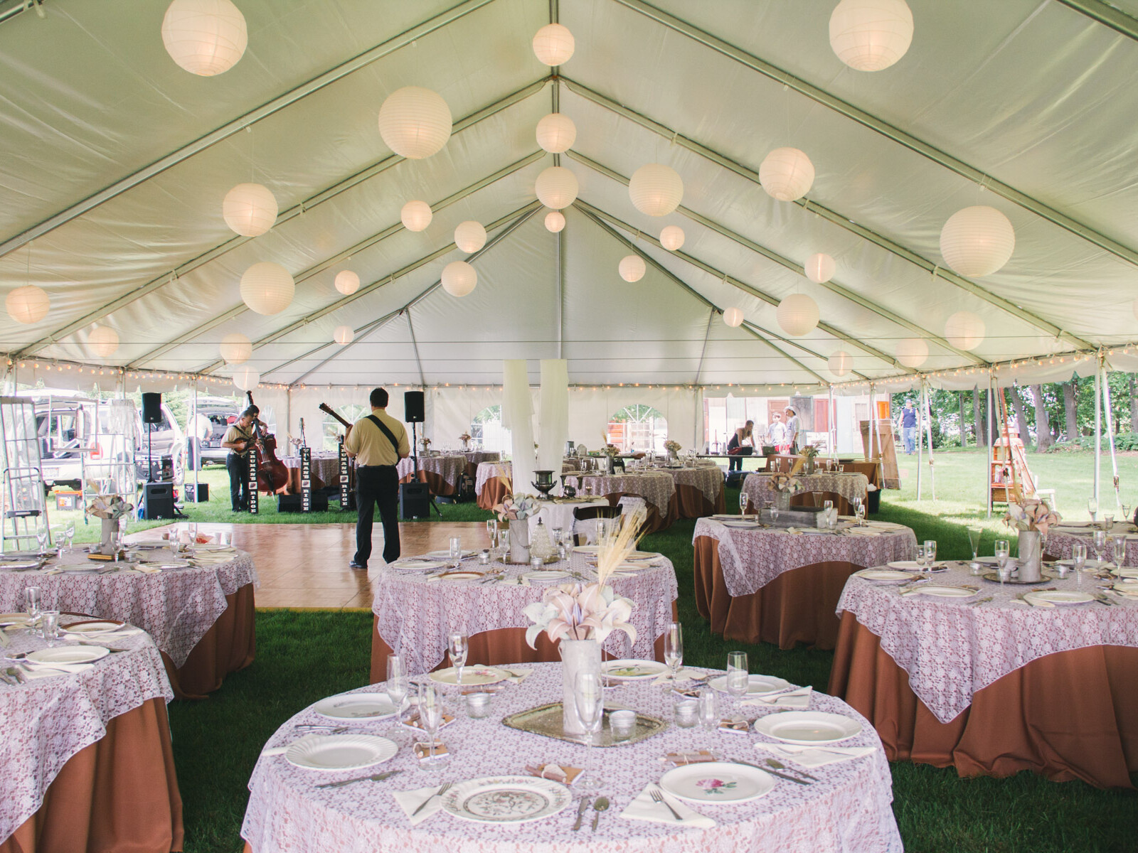 Inside a large frame wedding tent with globe lights, elegant tables and a dance floor.