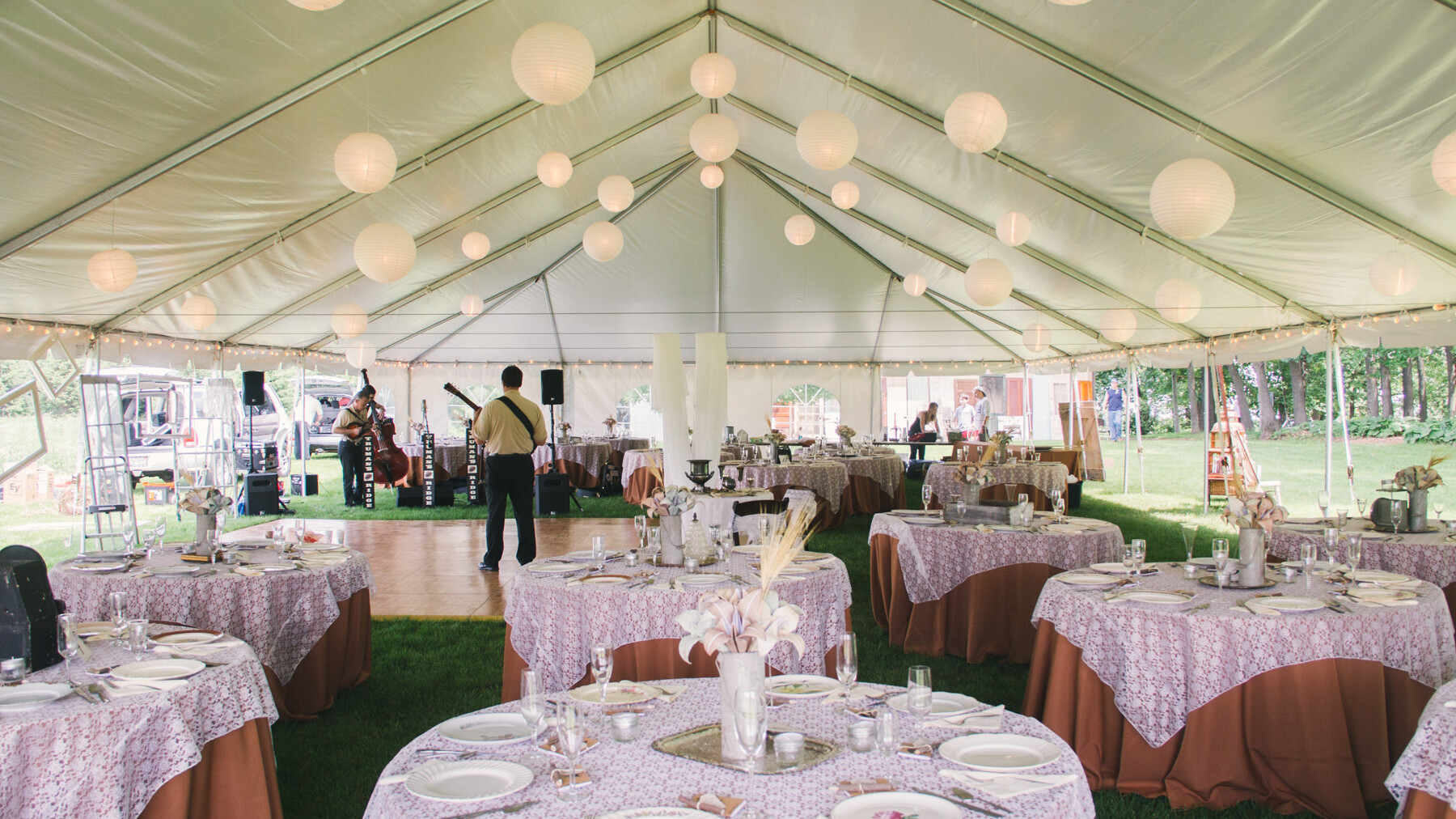 Inside a large frame wedding tent with globe lights, elegant tables and a dance floor.