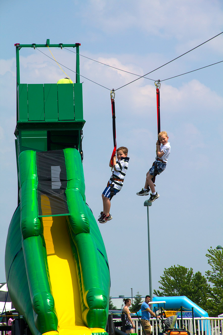 Two children enjoy a ride down our Naperville Zipline Rental